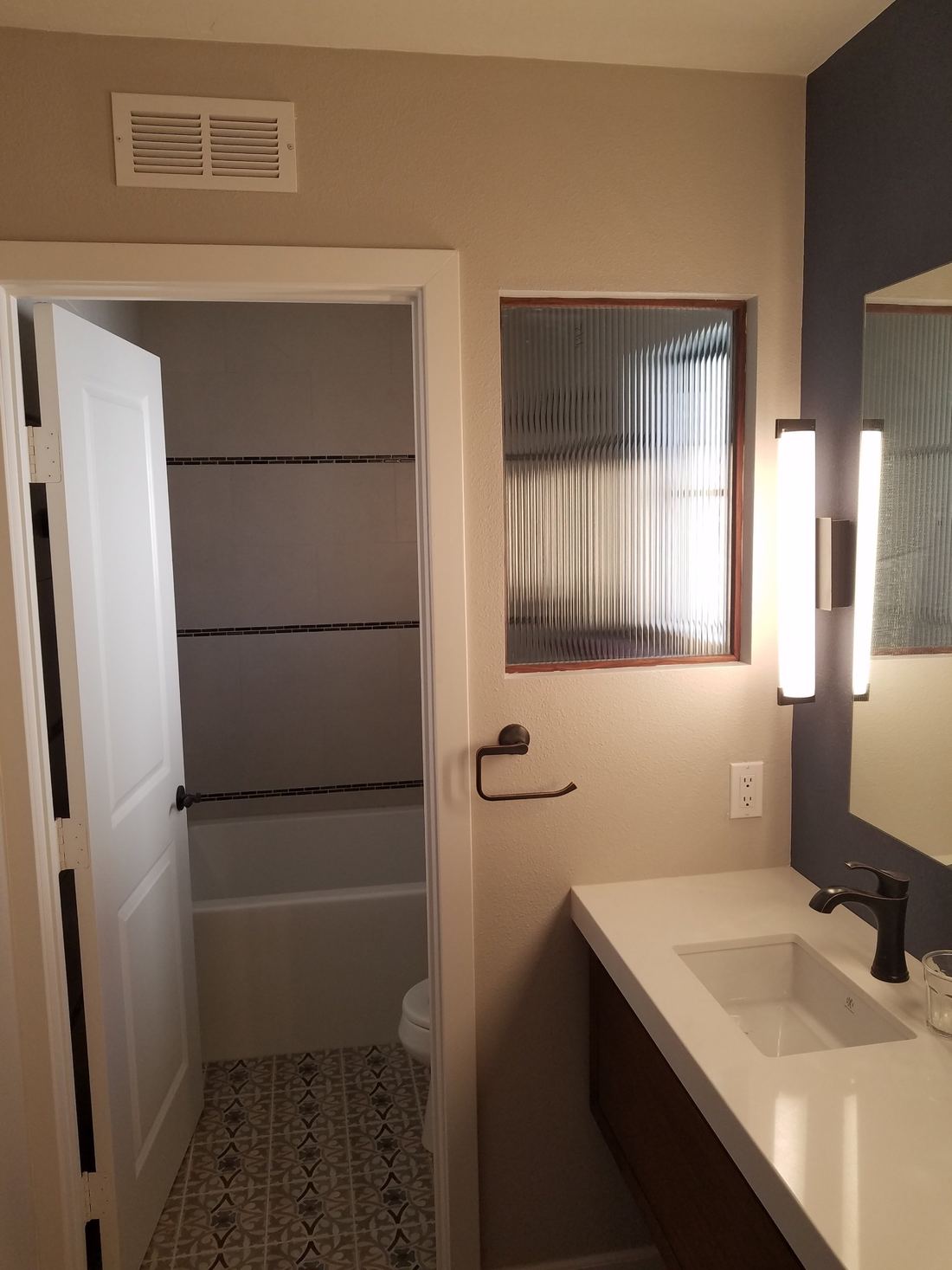 Separate tub room with accent-stripe tile