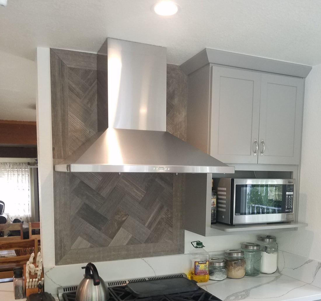 Range wall with a herringbone tile surround and chimney hood